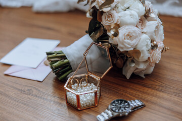 A bouquet of flowers sits on a wooden table next to a small box of pearls and a watch. Concept of...
