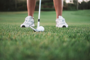 Close-up banner of the legs of a young woman playing golf on the green lawn of a country club. She...