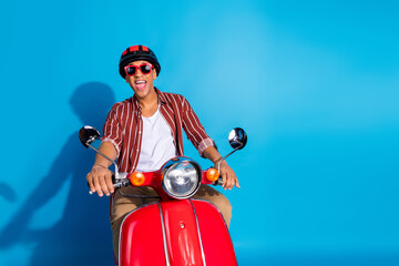 Photo of funky positive overjoyed guy wear striped stylish t-shirt helmet ride on moped having fun...
