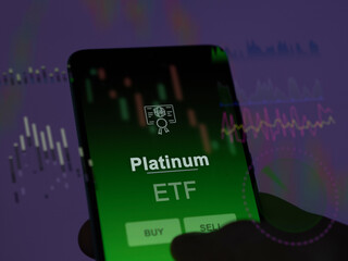 An investor analyzing the platinum etf fund on a screen. A phone shows the prices of Platinum