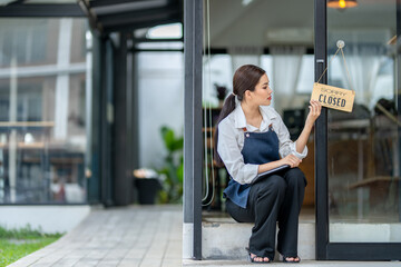 A woman sits on a sidewalk outside a closed restaurant