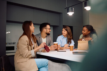 Happy start up team communicating while drinking coffee in office.