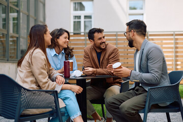 Cheerful coworkers drinking coffee and communicating at office building patio.