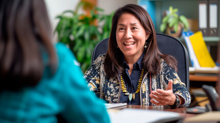 Fototapeta premium 50 year old female consultant, smiling, sitting at her desk talking to another person