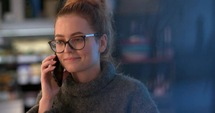 Young beautiful girl with glasses talks affably on a mobile phone.