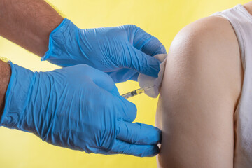 a doctor with gloves inoculates a person in the arm