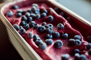 Close-up of fresh blueberries on top of the container full of blueberry gelato ice cream.