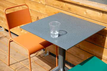 cafe table, chairs, and plastic cup with some water outdoors