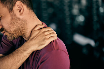 Close-up photo of a male who injured himself in the gym, holding his back muscle.