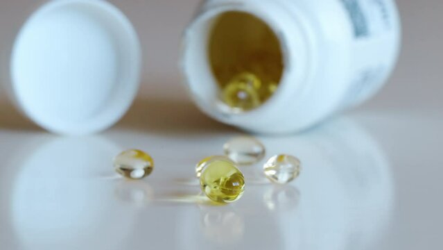 Fish oil omega 3 supplements spilling out of a packer bottle on a white background
