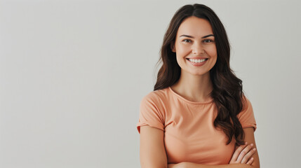 Obraz premium Confident woman smiling in a peach shirt, arms crossed