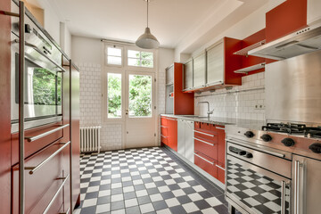 Modern kitchen with red cabinets and checkered floor in Rubensstraat