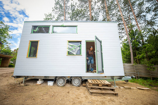 Young woman in a tiny house on a sunny day