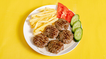 Grilled beef kofta and fries with vegetables on plate