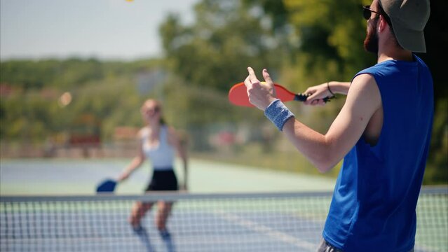 A man and a woman playing pickleball on a sunny day