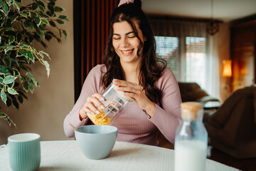 One young caucasian woman is eating corn flex breakfast at home before work	