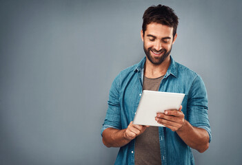 Fototapeta premium Man, tablet and scroll by white background with smile for social media, internet or website search. Fashion designer, happy and technology for b2b ecommerce, startup and online or digital catalog