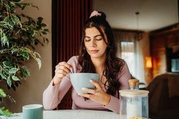 One young caucasian woman is eating corn flex breakfast at home before work	