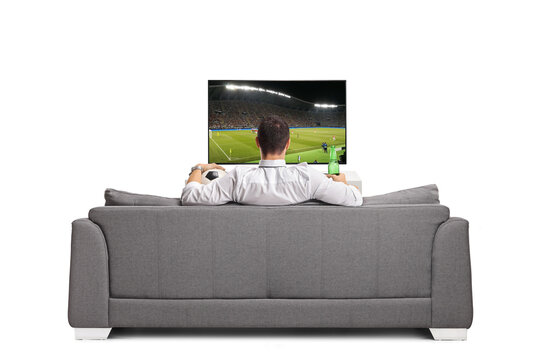 Man watching a football game on tv and holding a bottle of beer
