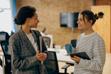 Smiling women colleagues speak laughing enjoy leisure time at workplace. Corporate culture concept