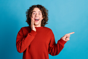 Photo of funky impressed guy dressed red pullover pointing finger emtpy space isolated blue color...