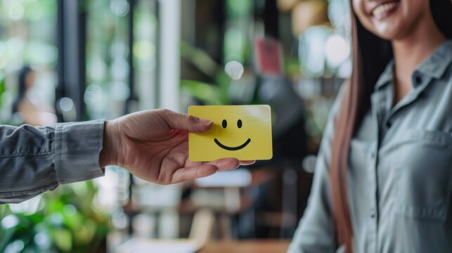 A customer experience concept is illustrated as a happy client woman provides feedback with a smiley face card to a businessman.