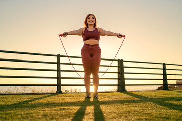 Plus-Size Woman Jump Roping Outdoors - Fitness Motivation at Sunset