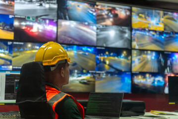 A man is seated at a desk in front of several monitors,  monitoring and analyzing data of the...