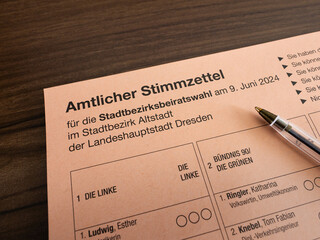 Amtlicher Stimmzettel (official ballot paper) for the Stadtbezirksbeiratswahl (municipal election) 2024 in Dresden, Germany. Pen lying on the voting document to make a choice.
