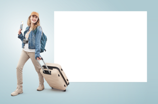 Happy young woman tourist traveling with trolley suitcase showing passport and flight ticket, isolated on background with a blank white billboard. Advertising banner with copy space for travel agency