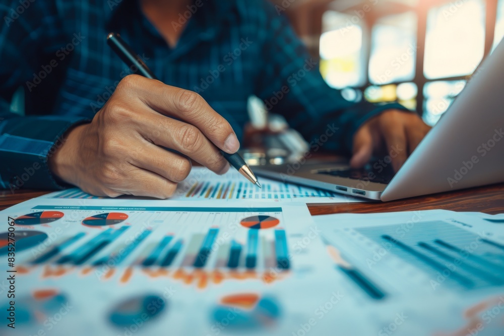 Poster close-up of hands scrutinizing business reports with charts and graphs indicating detailed performan