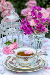 Tisch-Arrangement mit vintage Porzellan-Teetasse, Blumenstrauss mit Rosen und Duftwicke und Vogelkäfig	
