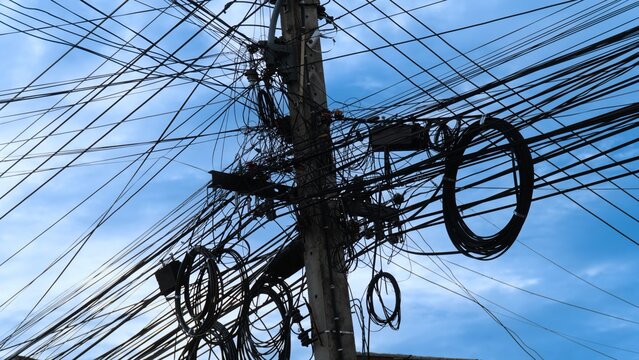 A tangled mess of wires and cables on a telephone pole.
