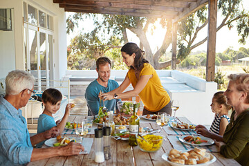 Happy family, eating and food with relax outdoor on patio with conversation, bonding and healthy meal in summer. Parents, grandparents and kids at dining table in backyard of home with talking or fun