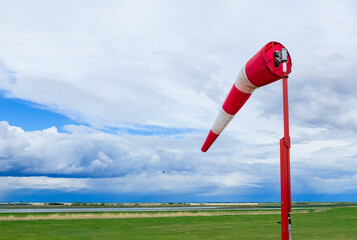 Weather vane in the airfield with grass and dramatic cloudy sky.
