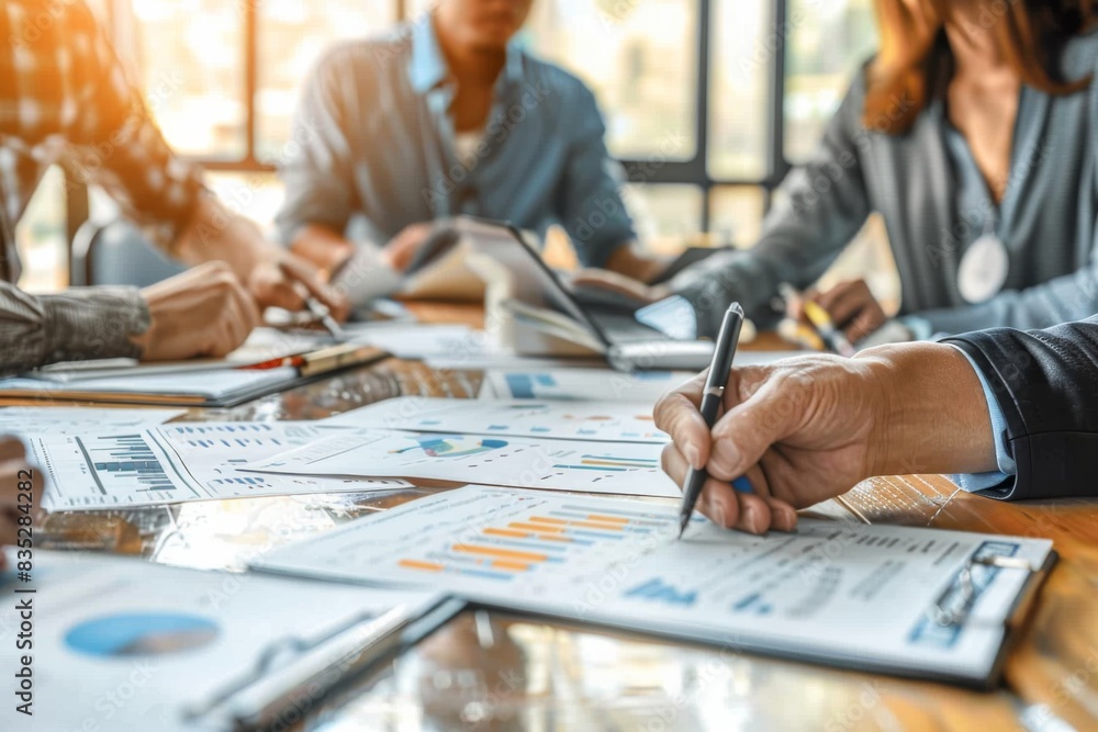 Poster a team of professionals is focused on discussing and analyzing financial charts and data on paper in