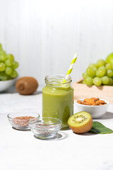 healthy superfood - green smoothie made from fruits and herbs on white table, vertical
