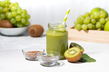 healthy superfood - green smoothie made from fruits and herbs on white table, closeup