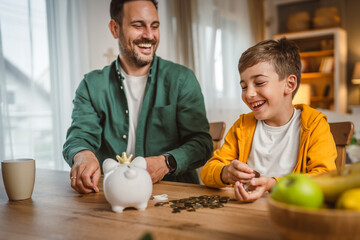 Father and son save money coins together at piggy bank at home