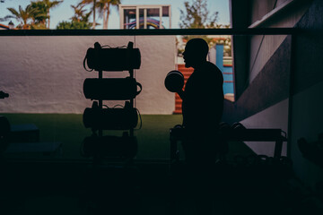 Silueta en negro de hombre entrenando con pesas en un gimnasio al aire libre