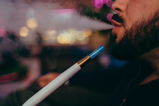Detalle de labios expulsando humo de cachimba con fondo muy desenfocado