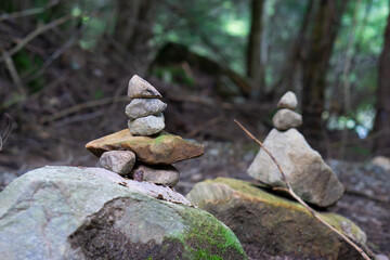 Stone cairns or rocks pyramids at the forest in Quebec, Canada. Close up of stacks of rocks on the river bank in a forest.