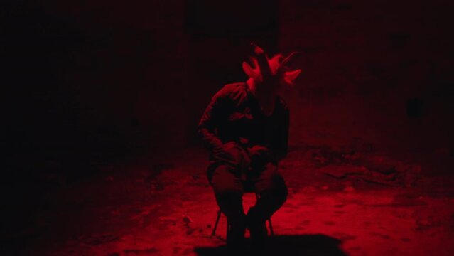 Tortured man in a mask, tied to a chair.