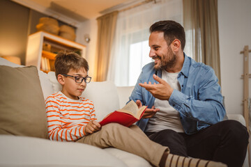 Father and son read a book and have fun while spend time together