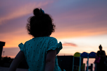 Child silhouette  against purple pink summer sunset. Childhood concept. Travel destination kids beach.