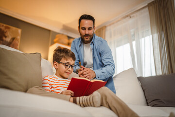 Father look at his son how read a book and spend time together at home