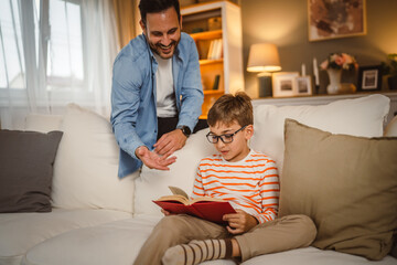 Father look at his son how read a book and spend time together at home