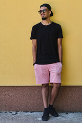 Middle Eastern Teenager Leaning Against Yellow Wall in Casual Attire