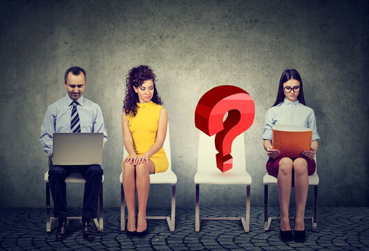 people waiting for business job interview with one empty question mark chair