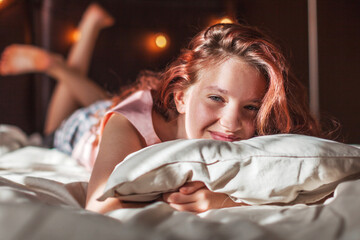 Happy young girl lying in bed in the morning - Powered by Adobe